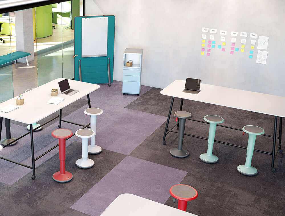 Modern office space with ergonomic UPis1 90 Junior stools in various colors, featuring 360-degree rotation and adjustable height.