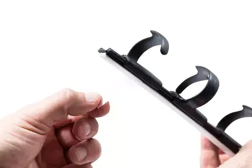 Close-up of a hand holding a RIB cable tray, showing its hooks for organizing cables under a desk.