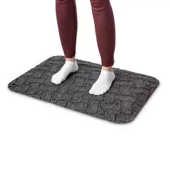 Person standing on grey ergonomic fabric workstation mat for comfort and support.