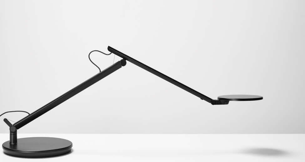 Black Nova desk lamp with adjustable arm on a desktop base against a light background.