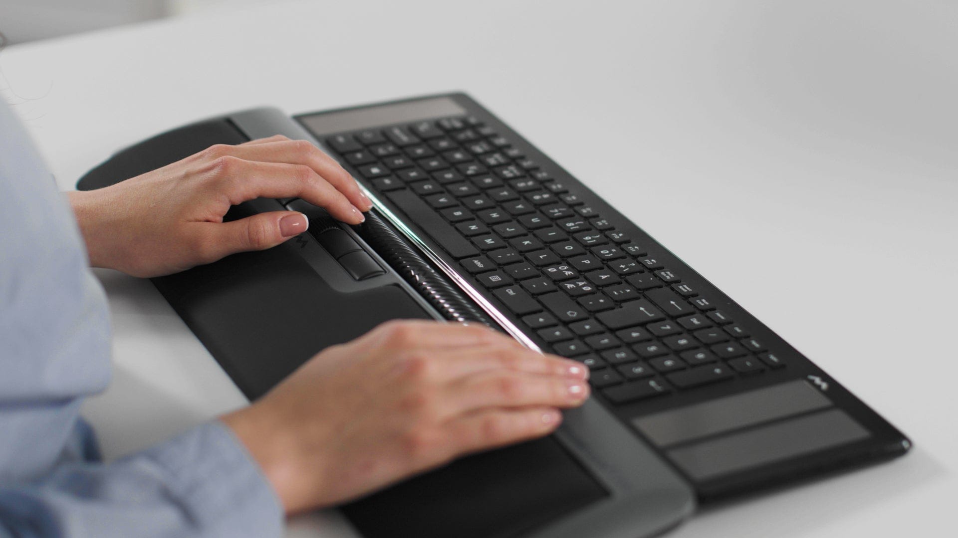 Person using the Mousetrapper Delta Extended grey keyboard with ergonomic design and programmable buttons for precise navigation.