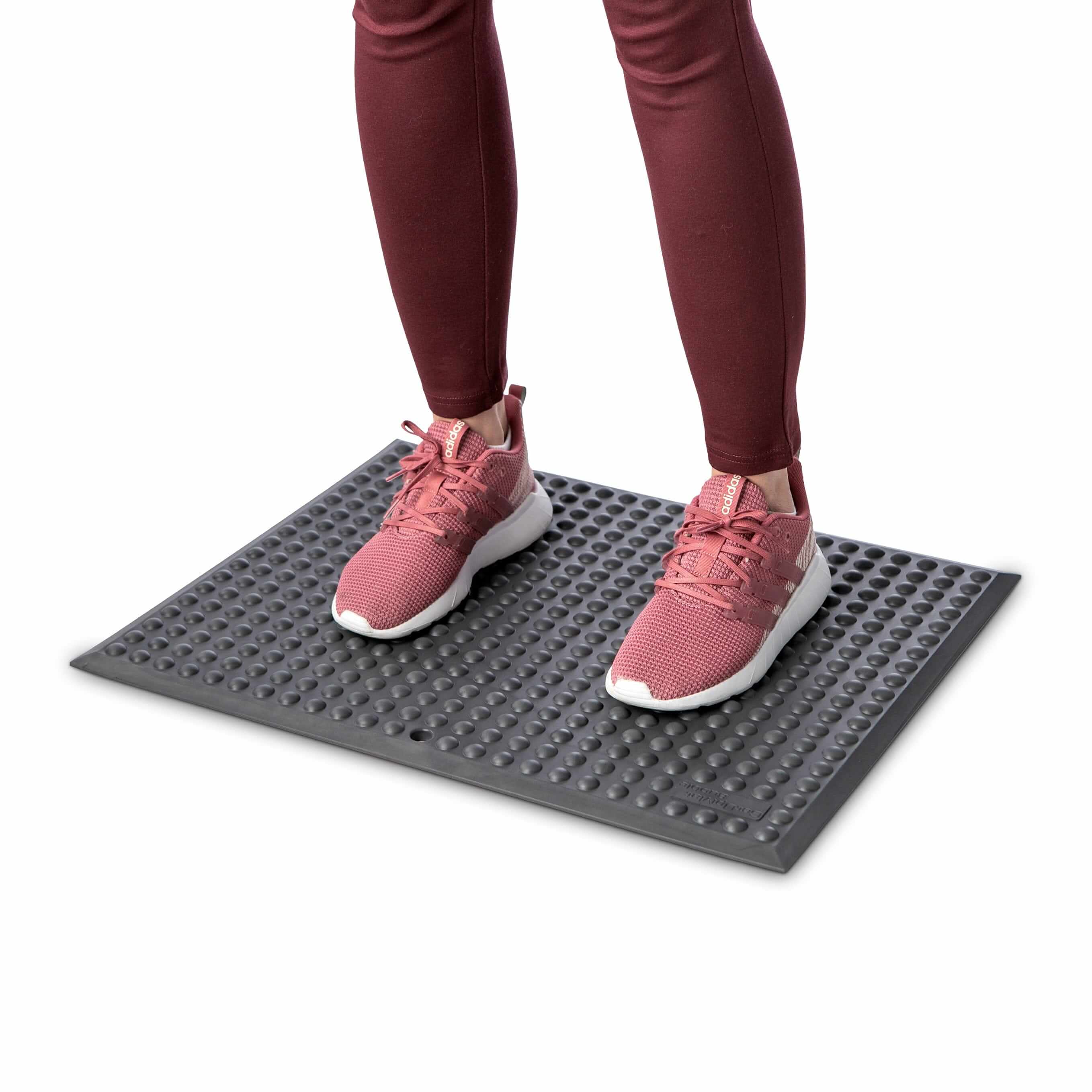 Person standing on GetUpMat Bubble workstation mat in grey for improved circulation and reduced fatigue during office work.