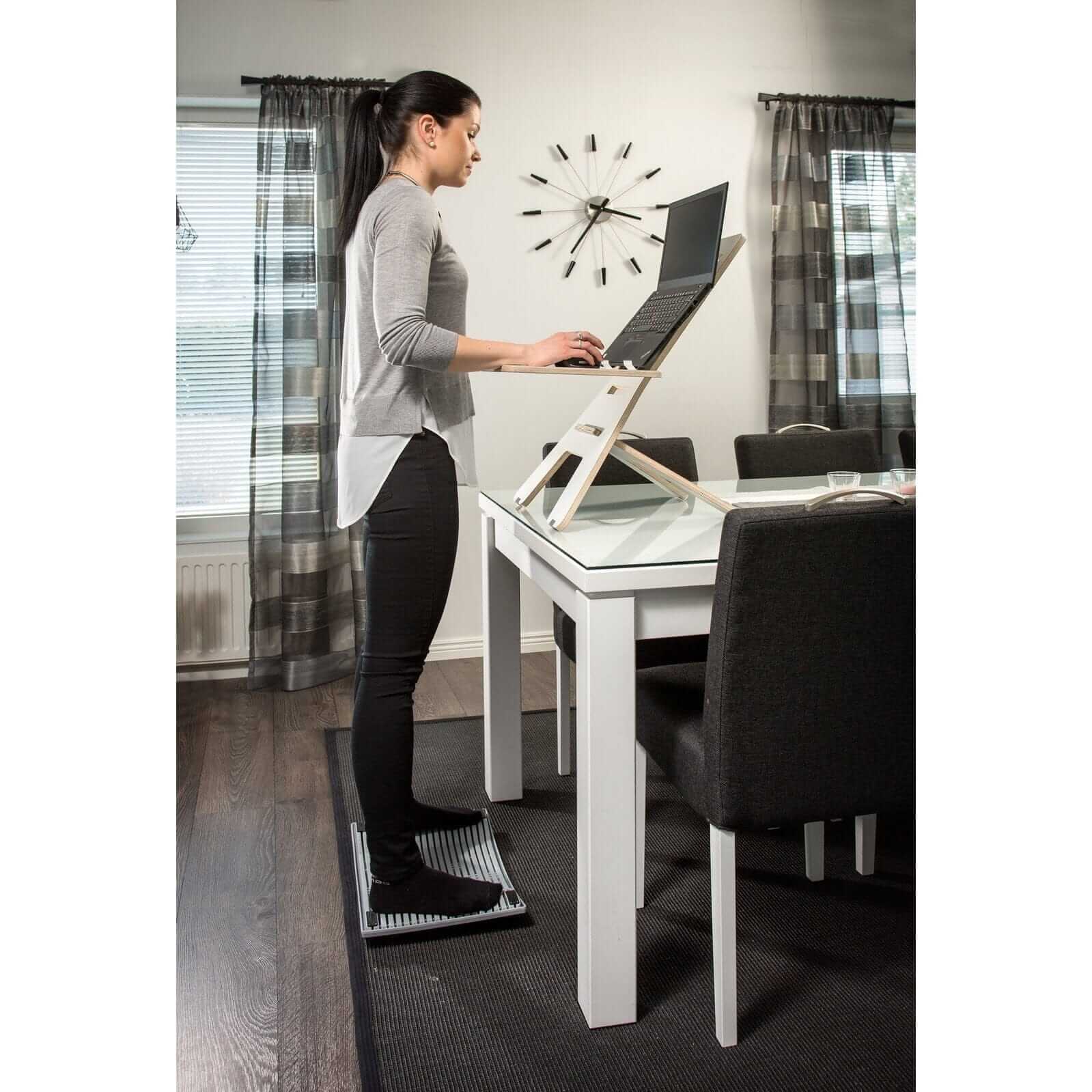 Woman using a Gymbailu activation board at a standing desk to enhance movement and boost metabolism at work.