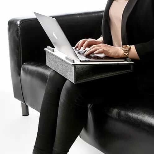 Woman using Läpsteri laptop stand in Arctic White on sofa, enhancing ergonomic productivity.