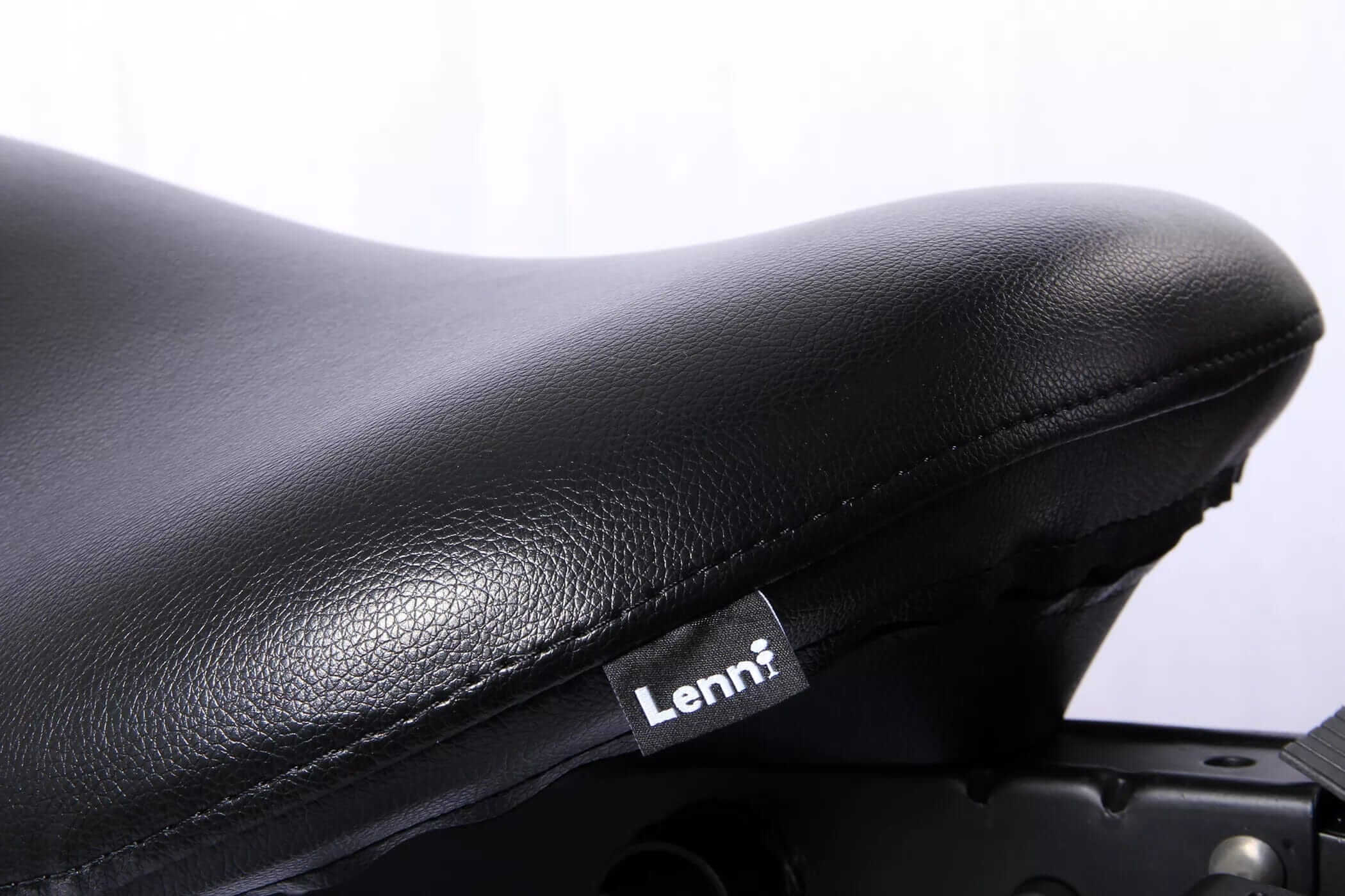 Close-up of Lenni saddle chair with black artificial leather upholstery showing ergonomic design and stitching details.